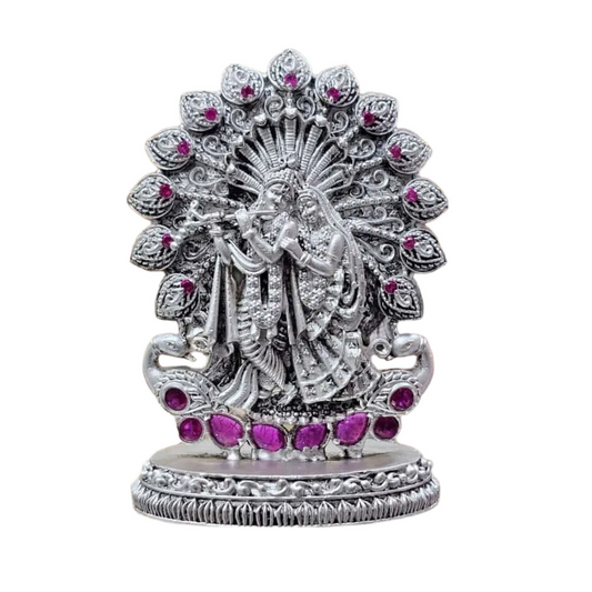 925 silver Radha Krishna idol with intricate detailing and pink gemstone accents on a decorative base